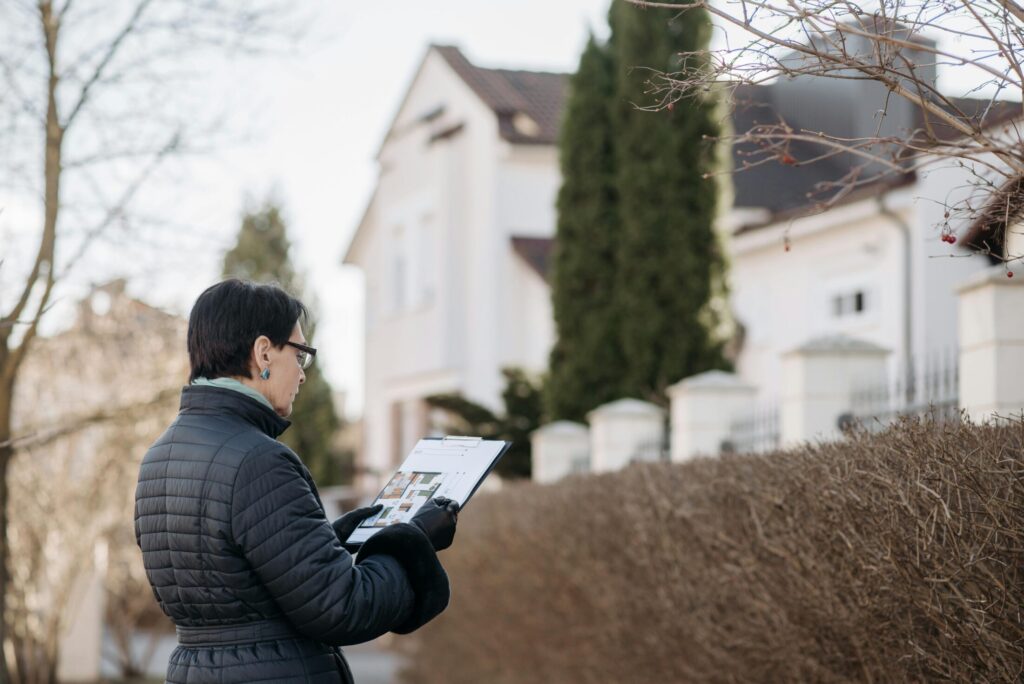 a woman standing on the street holding a house plans